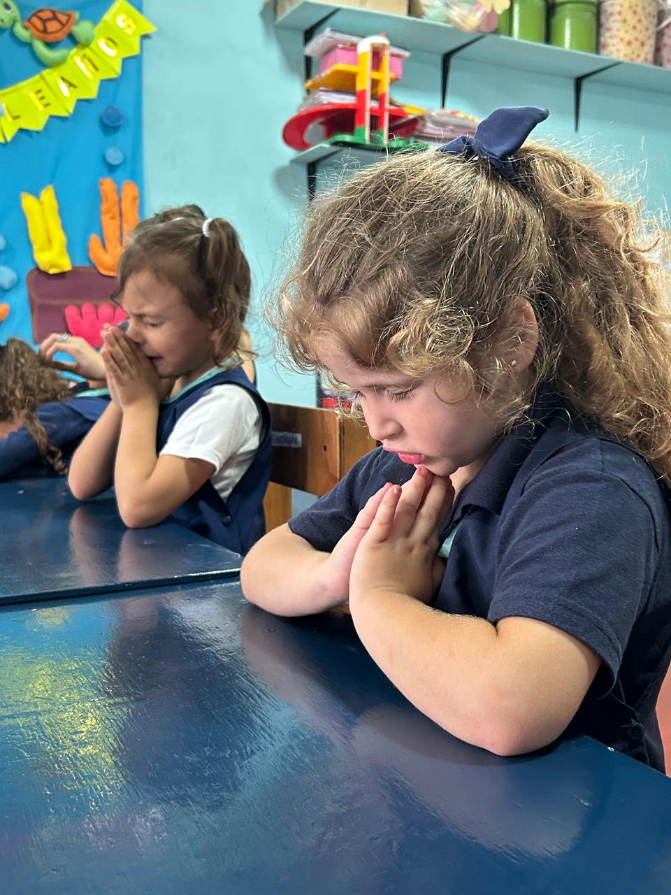 Niñas orando en el aula.